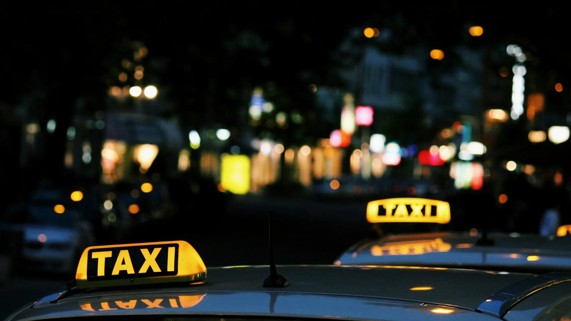 Leuchtende Taxischilder im nächtlichen Stadtverkehr