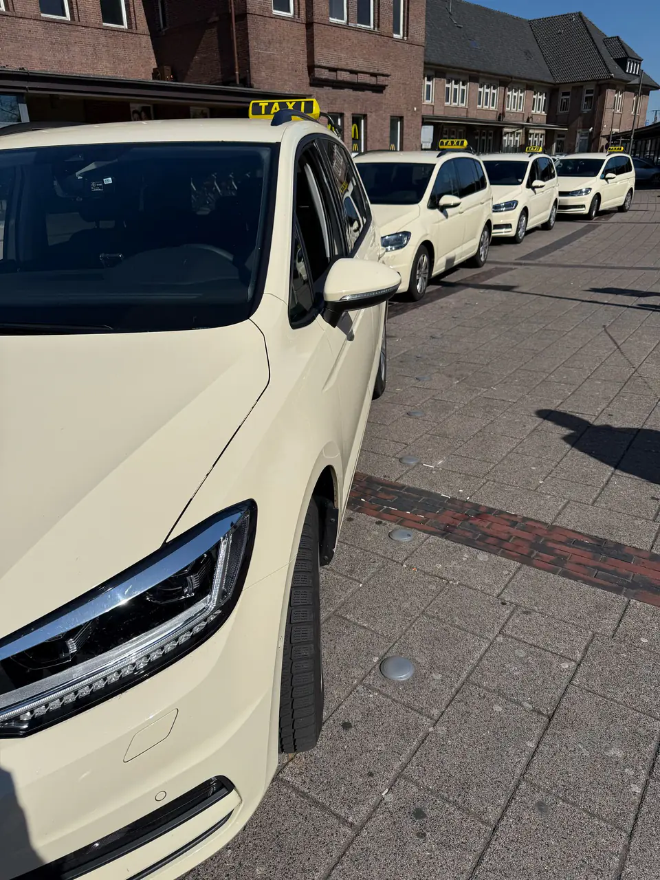 Mehrere helle TaxiGo-Fahrzeuge vor dem Hauptbahnhof Oldenburg